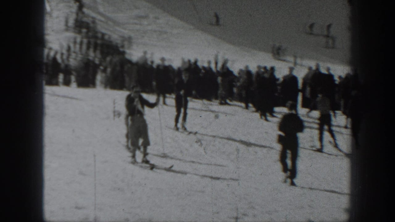 1940 Washington home-movie frame showing skiers descending a snowy slope as bundled onlookers gather near the top.