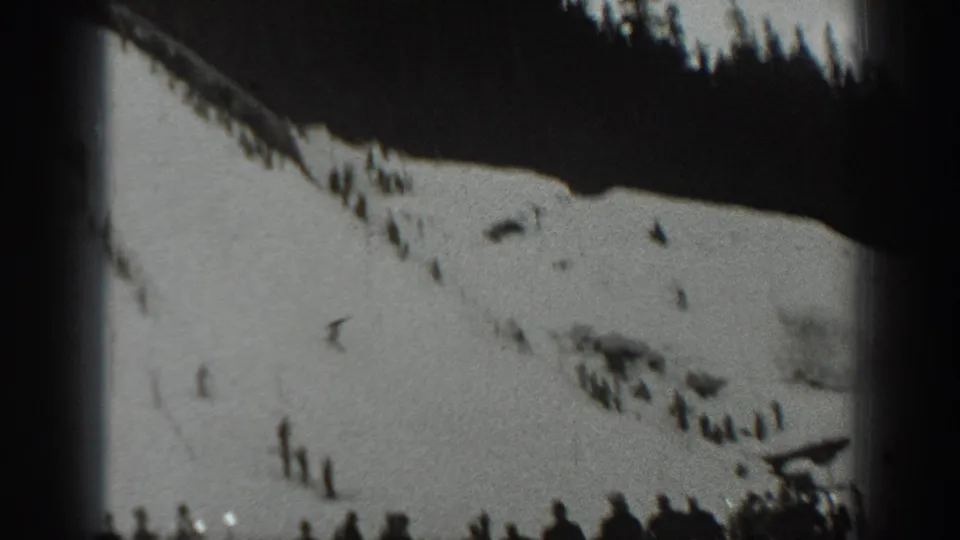 Wide 1940 Washington skiing view with small figures on a snowfield below a dark pine-covered ridge.