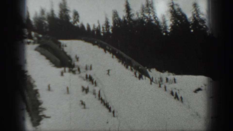 1940 Washington 8mm frame showing a busy snowy hill where distant people sled, stand, and wait near the slope.