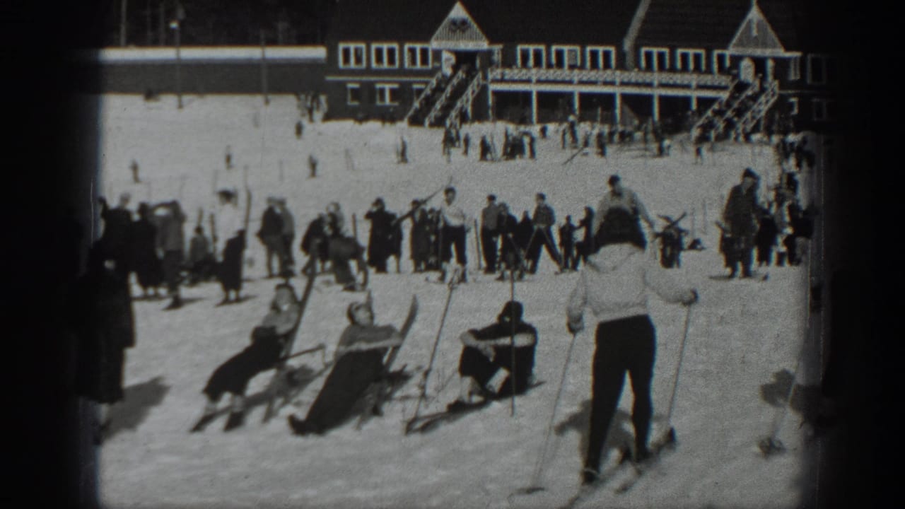 1940 Washington home-movie frame showing skiers and onlookers gathered on snow near a large resort lodge.