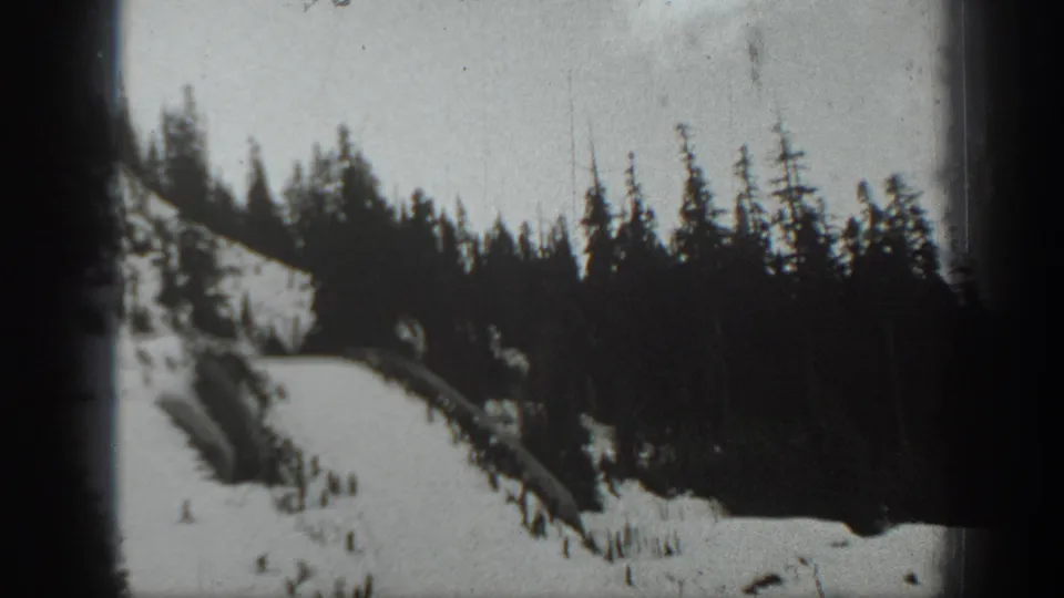 Home-movie view of a Washington ski slope, with evergreen forest and distant people on the snow.