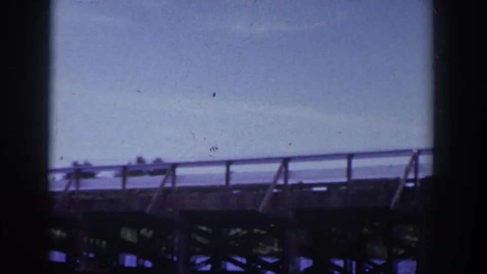 1953 Wisconsin 8mm frame showing a bridge or dock structure over lake water from a motorboat viewpoint.