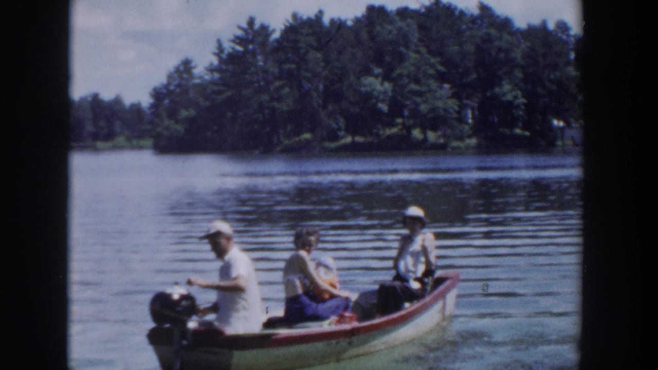 1953 Wisconsin lake scene with a man steering a small outboard motorboat while two adult passengers sit behind him.