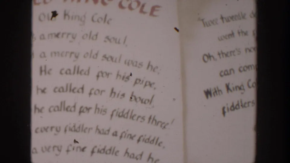 1954 Wisconsin Dells home-movie frame showing a hand-lettered Old King Cole rhyme page with dark vertical frame edges.