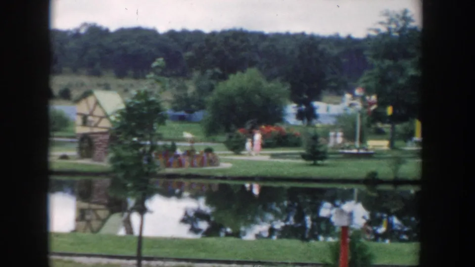 The 1954 Wisconsin Dells footage shows visitors moving through a landscaped miniature-golf village beside a reflective pond.