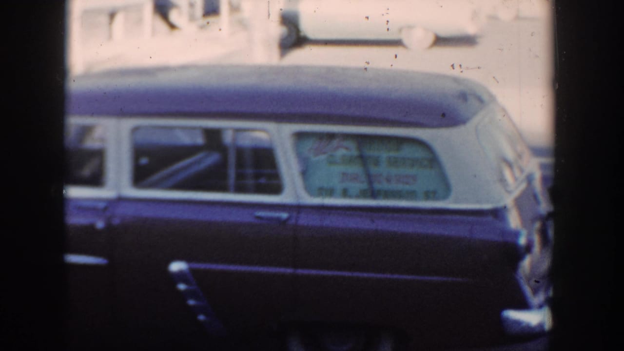Cropped 1954 Wisconsin Dells home-movie view of the station wagon, showing rear glass lettering, side trim, and worn 8mm texture.