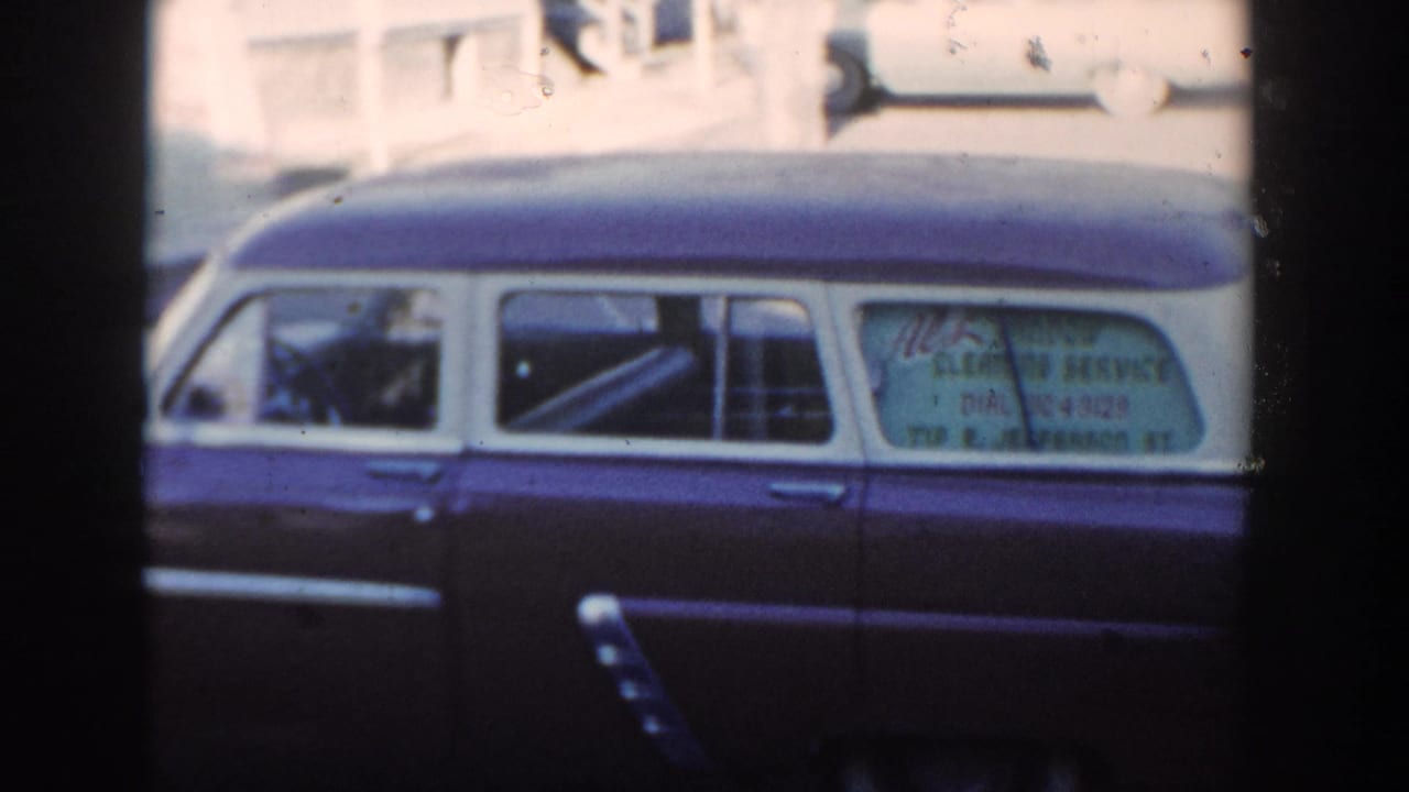 1954 Wisconsin Dells frame showing the full side of a two-tone station wagon, with a person faintly visible near the front seat area.
