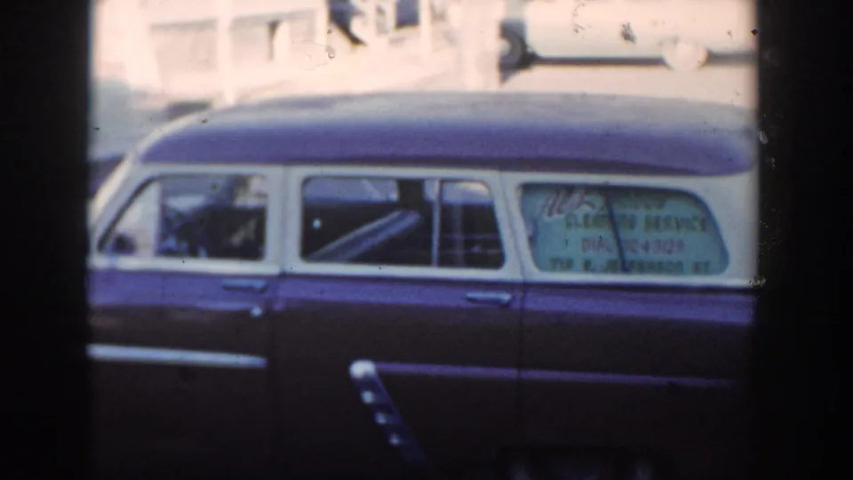 1954 Wisconsin Dells frame showing the full side of a two-tone station wagon, with a person faintly visible near the front seat area.