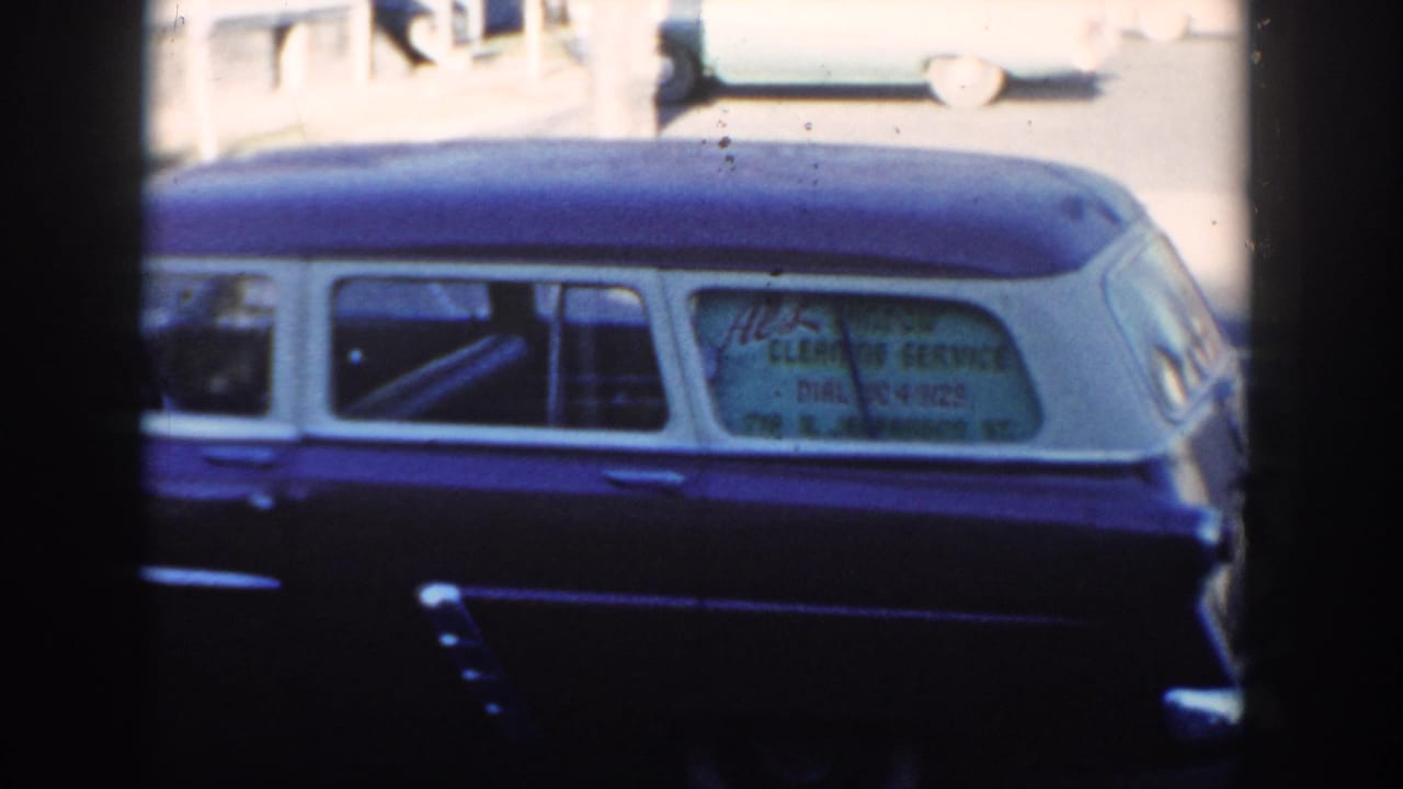 Cropped 1954 Wisconsin Dells view of the two-tone wagon, emphasizing the side windows, white roof, and service advertisement text.