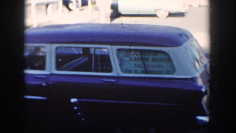 Cropped 1954 Wisconsin Dells view of the two-tone wagon, emphasizing the side windows, white roof, and service advertisement text.