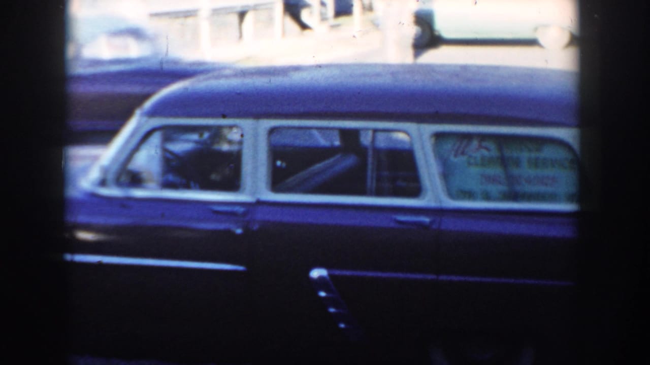 1954 Wisconsin Dells roadside frame with the parked two-tone wagon in front and a blurred passing car behind it.