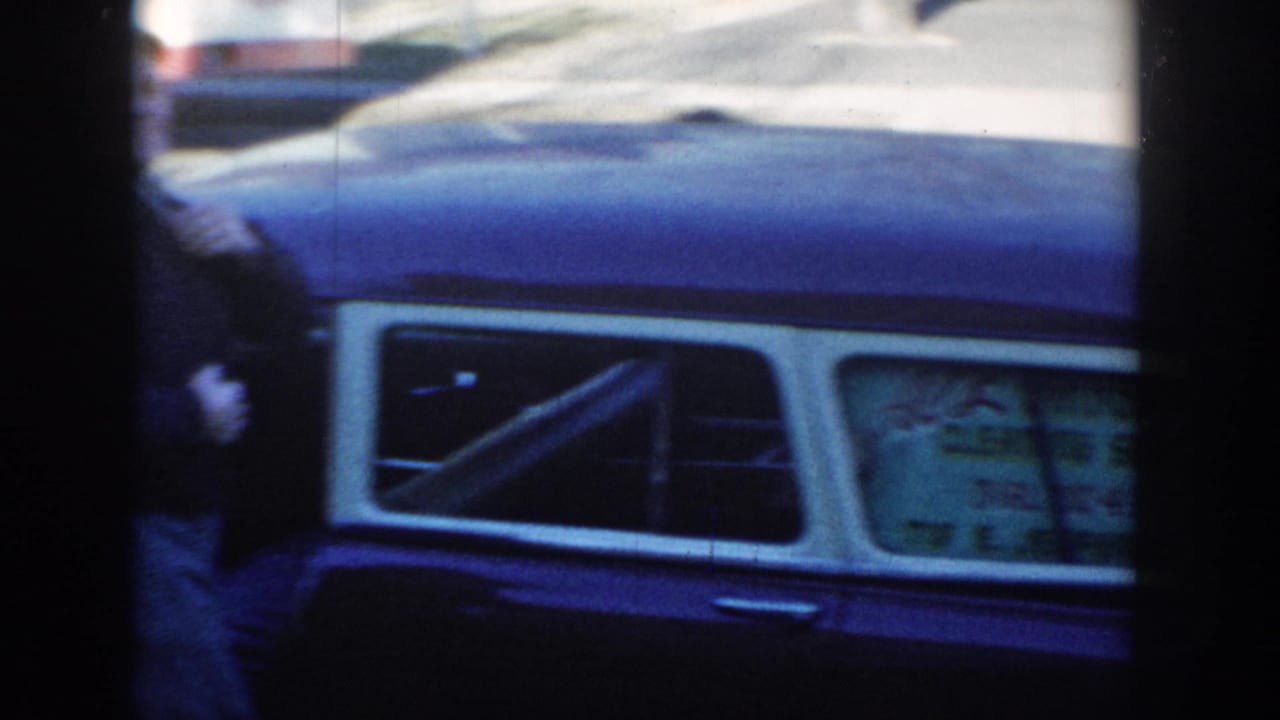 The blue car dominates the final frame, with a blurred person near the side and a partially visible sign or graphic in the rear window.