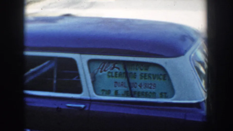 1954 Wisconsin Dells frame with the blue station wagon cropped tightly around the rear-window cleaning service advertisement.