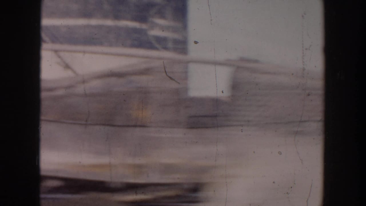 Blurred train or rail-side structure seen behind dark vertical frame edges.