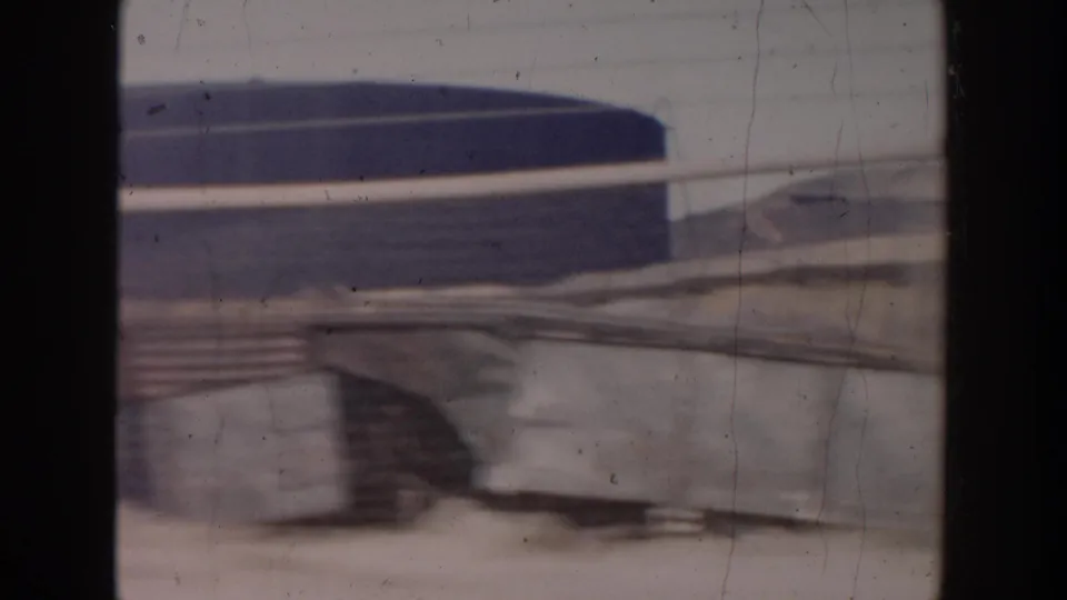 Motion-blurred 1956 Grand Rapids rail-side view with a train passing in front of industrial structures.
