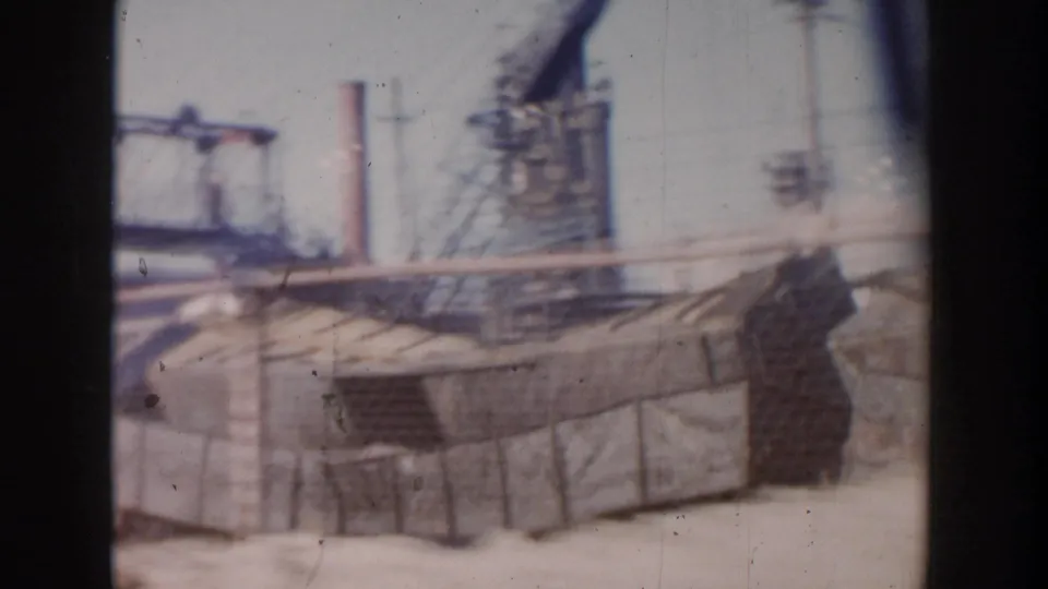 1956 Grand Rapids industrial yard view with smokestacks, fencing, utility structures, and weathered 8mm texture.