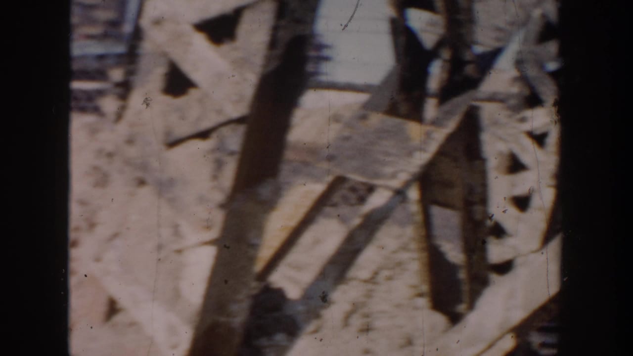 Close view of broken boards or barrier pieces over sandy ground.