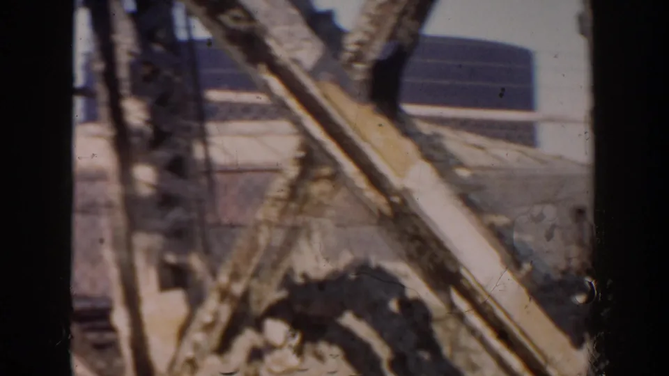 End frame showing crossed boards or metal pieces at the construction site, with a low building beyond in Grand Rapids.