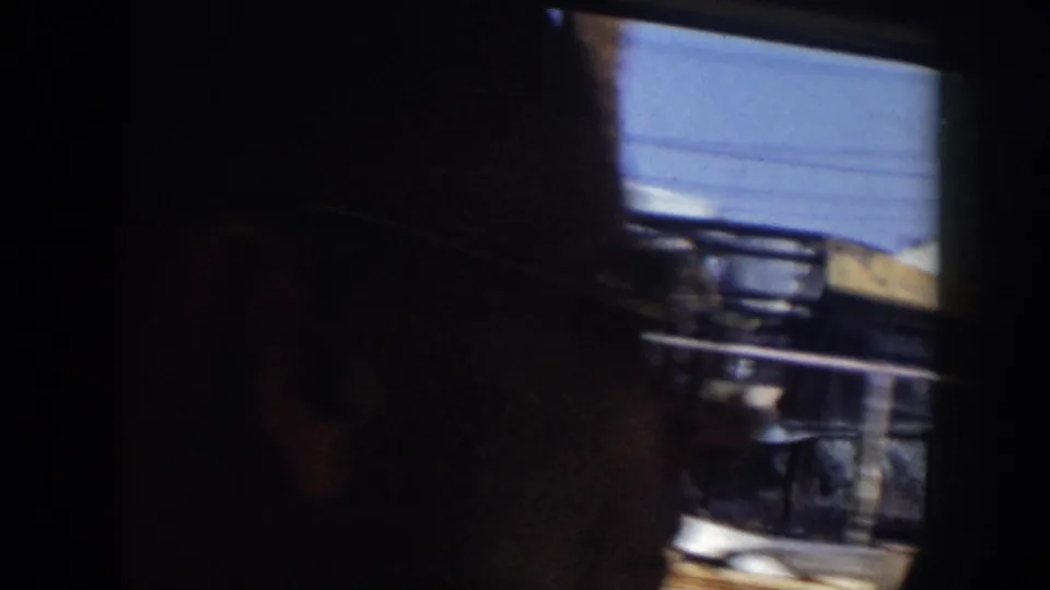 A passenger silhouette sits against the window as the 1956 Grand Rapids footage passes a blurred construction area outside.