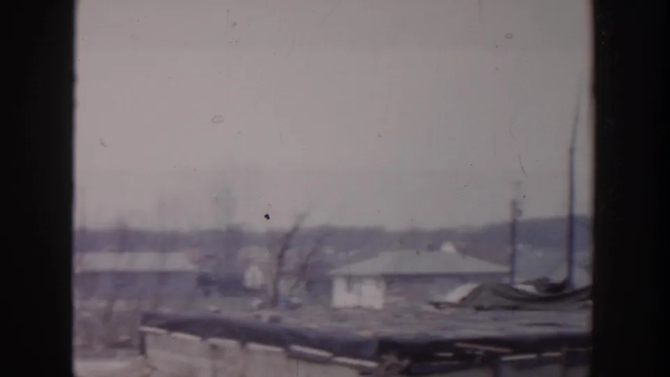 1956 Grand Rapids residential view with low rooftops, utility poles, and bare trees in faded 8mm color.