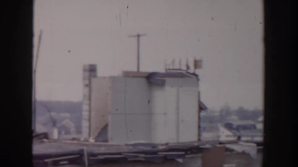 1956 Grand Rapids footage shows a pale rooftop structure, utility poles, and dark window framing across a flat roof.
