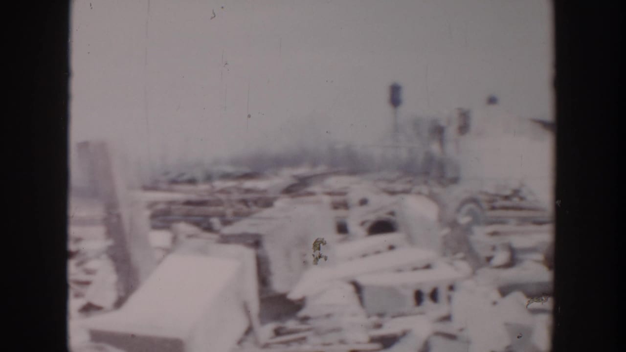 Snowy marina wreckage with damaged boats, dock pieces, and shoreline structures.