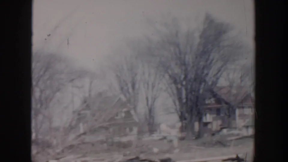 Grand Rapids 1956 frame with houses set back behind mature bare trees during a slow neighborhood pan.