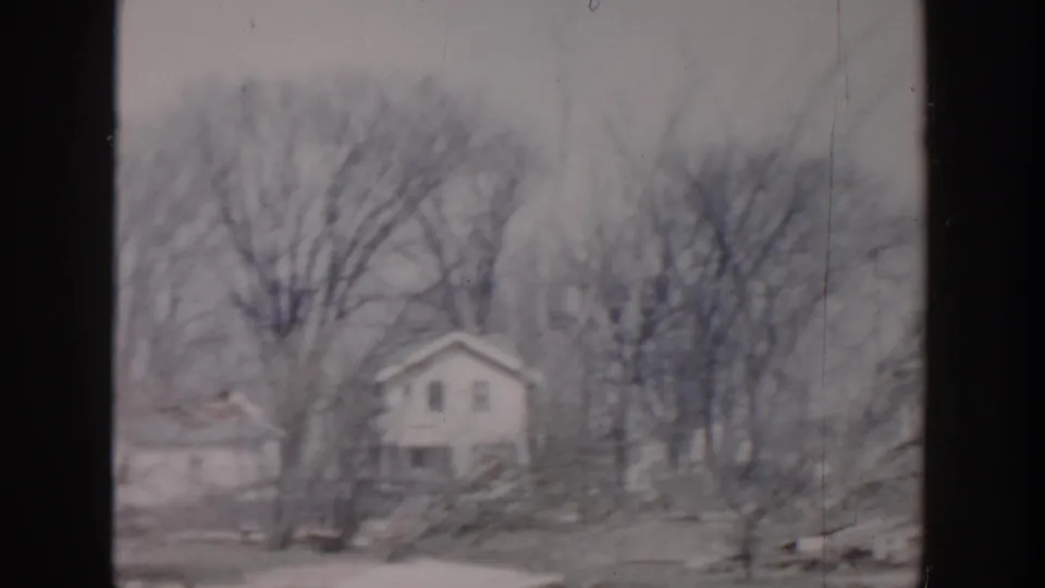 Grand Rapids 1956 home-movie view of a modest light-colored house framed by leafless trees and yard space.