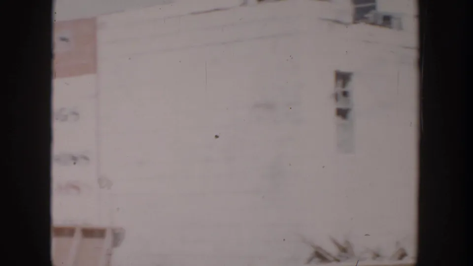 1956 Grand Rapids frame showing a pale, overexposed building exterior with small windows and dark 8mm frame edges.