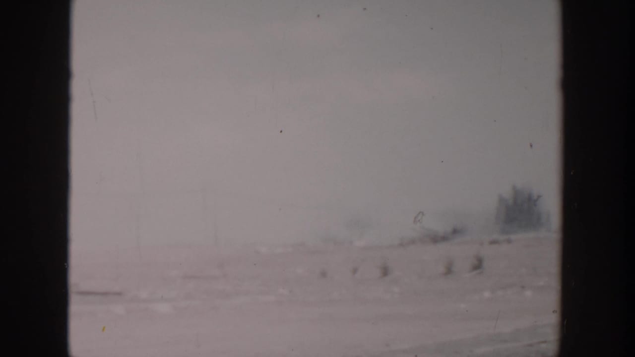 A hazy roadside view in 1956 Grand Rapids-area home-movie footage, with soft focus and visible film gate edges.