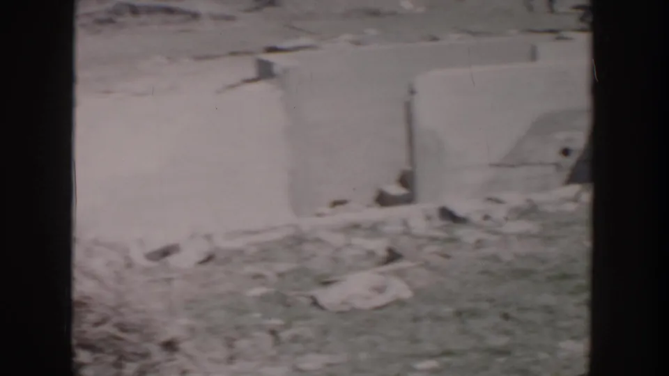1956 Grand Rapids frame showing a damaged exterior wall, roof covering, and scattered debris near the chapel sign area.