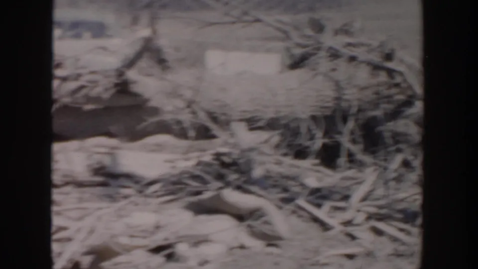 Soft 8mm frame of branches, boards, and mixed debris on bare ground, consistent with cleanup or clearing footage.