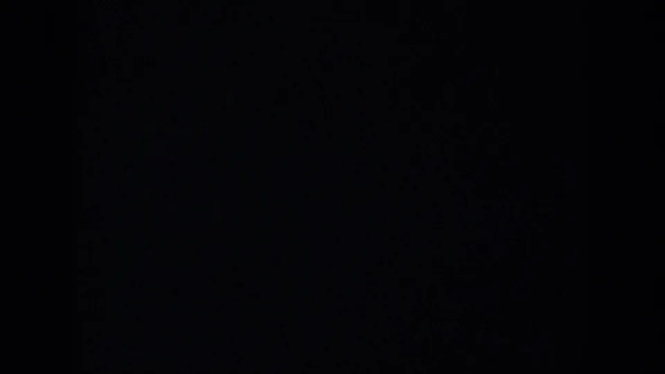 Underexposed 8mm frame from the 1957 Wisconsin clip, with the landscape largely obscured by dark film border or shadow.
