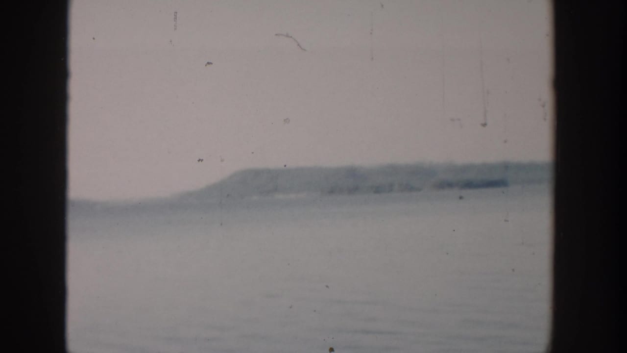 Hazy lake and distant low hills seen between dark vertical window-frame edges.