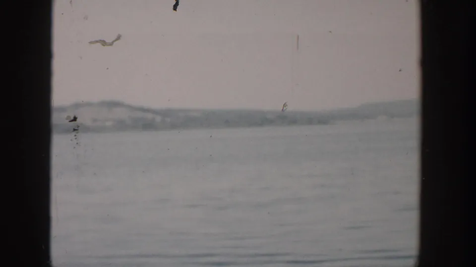 1957 Wisconsin 8mm waterscape with a distant low shoreline, soft focus, and visible home-movie film wear.