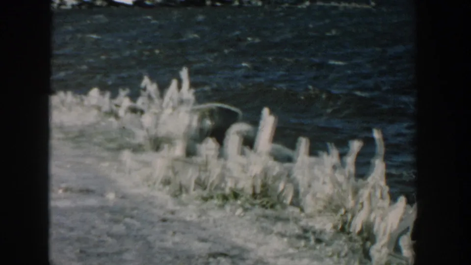 1957 Wisconsin home-movie frame of rough water and white ice formations along a frozen shore.