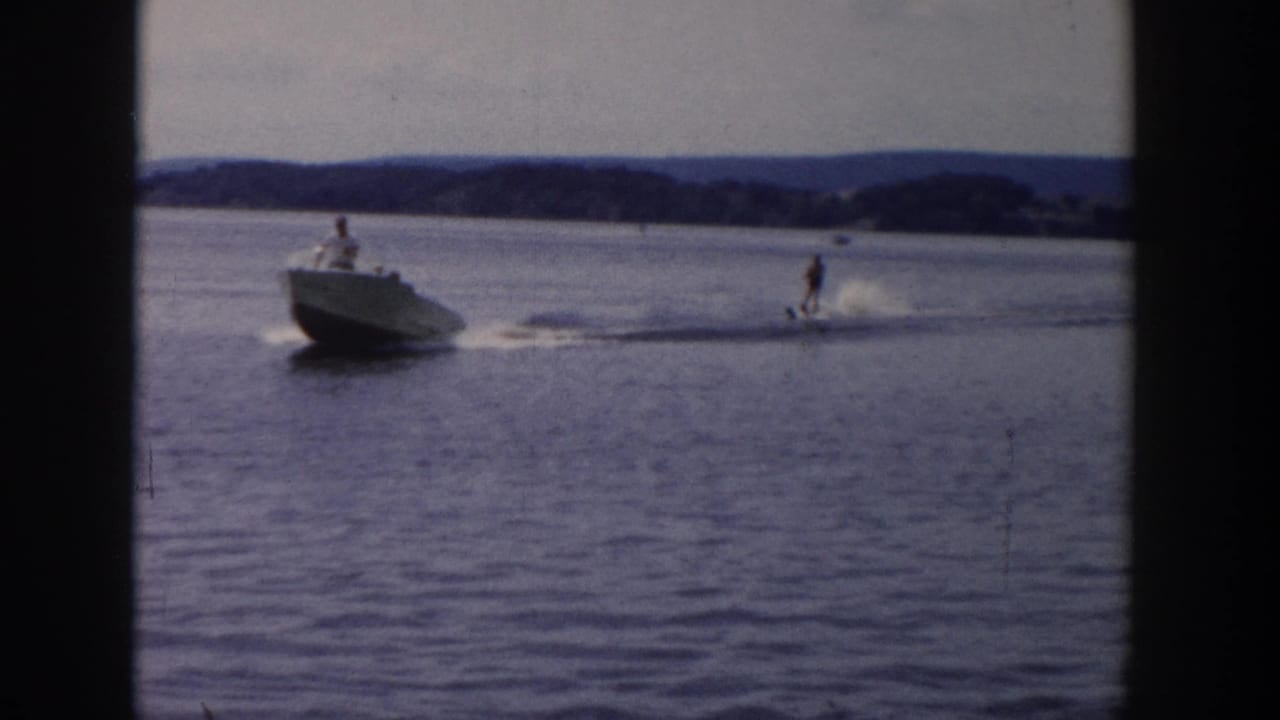 1958 Wisconsin waterskiing frame with a motorboat pulling a skier across calm lake water.