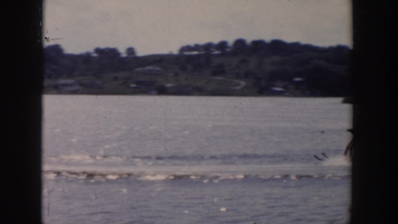 Lake surface and distant shoreline with a wake crossing the frame.