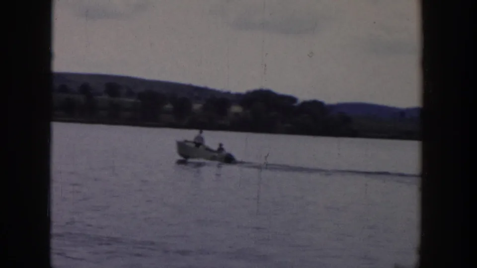 A small motorboat carrying visible occupants moves across the Wisconsin lake, towing the water skier outside the frame.