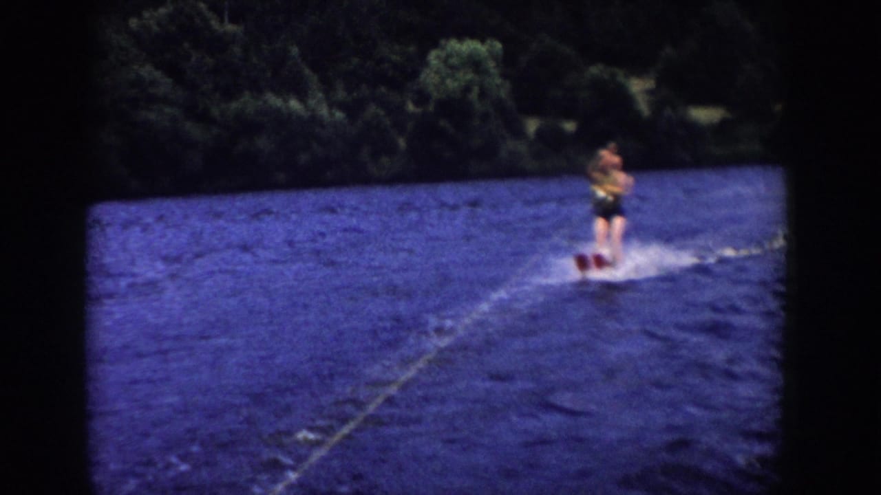 Soft 8mm frame of a skier leaning on paired skis during a 1958 Wisconsin lake outing.