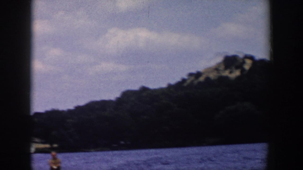 A soft 8mm view of a Wisconsin lake and tree-covered hillside, with the water skier only partly visible near the bottom edge.