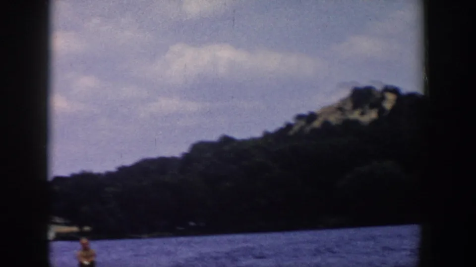 A soft 8mm view of a Wisconsin lake and tree-covered hillside, with the water skier only partly visible near the bottom edge.