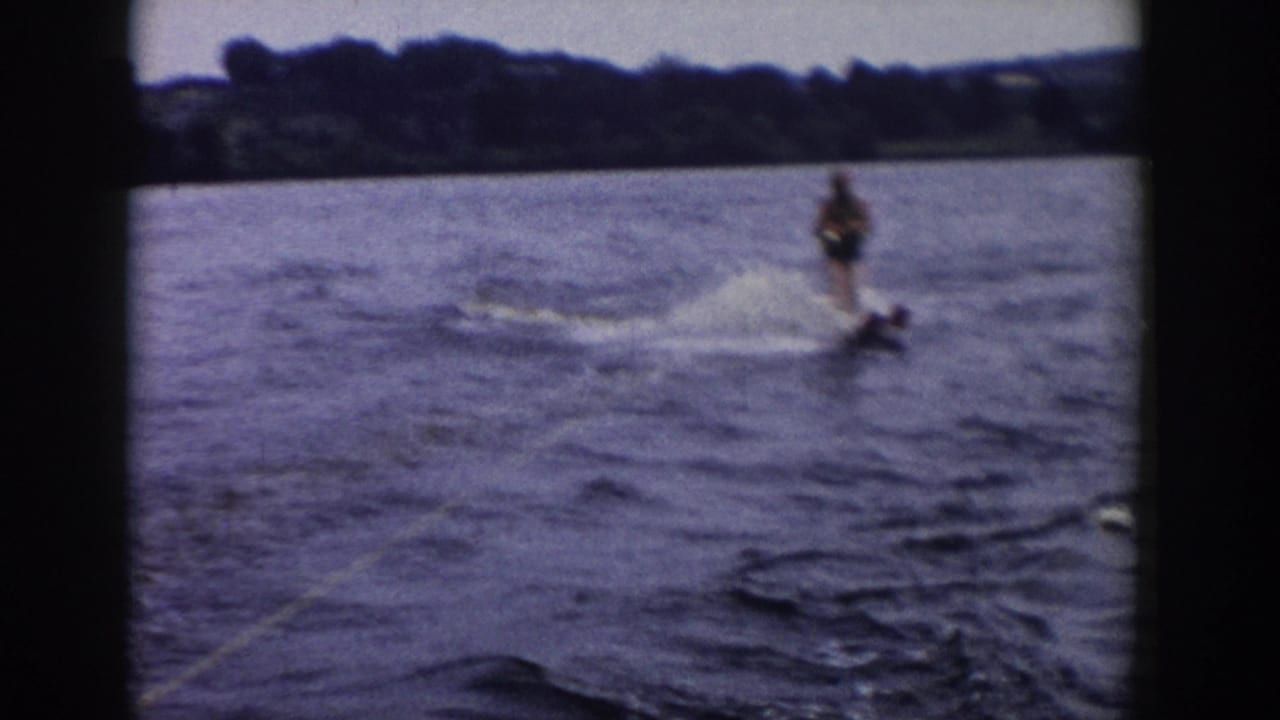 Water skier leans across the wake while spray rises on a lake.