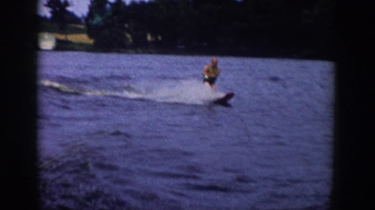 1958 Wisconsin 8mm frame showing a water skier crossing the lake in soft, grainy home-movie color.