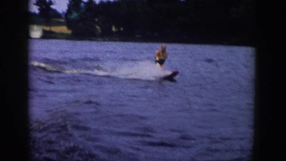 1958 Wisconsin 8mm frame showing a water skier crossing the lake in soft, grainy home-movie color.