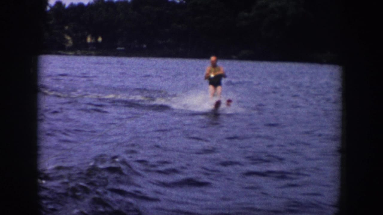 Man waterskiing on a lake with trees along the far shoreline.