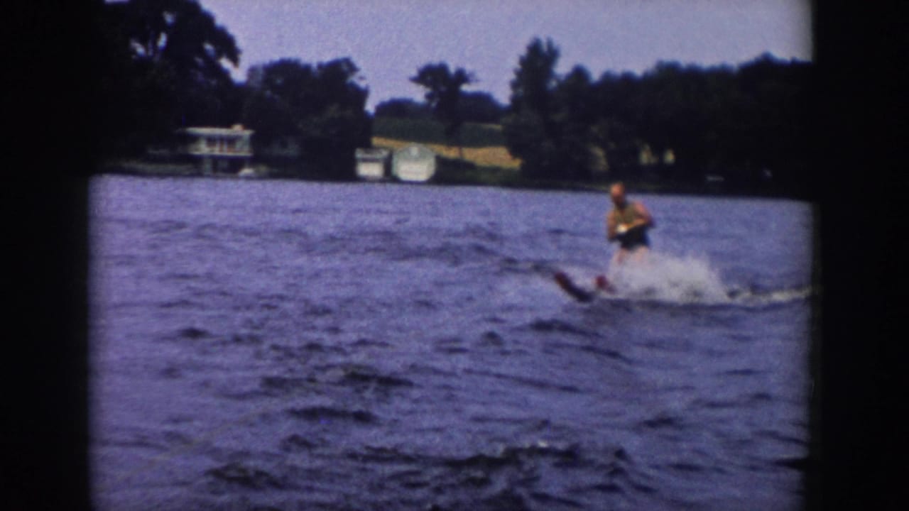 Waterskier leaning near the right side of the frame with spray behind him.