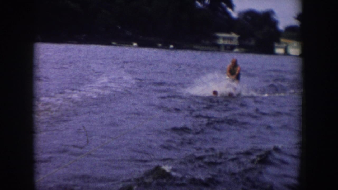 A soft 8mm frame from 1958 Wisconsin shows the skier amid spray, with the lake and distant trees filling most of the view.