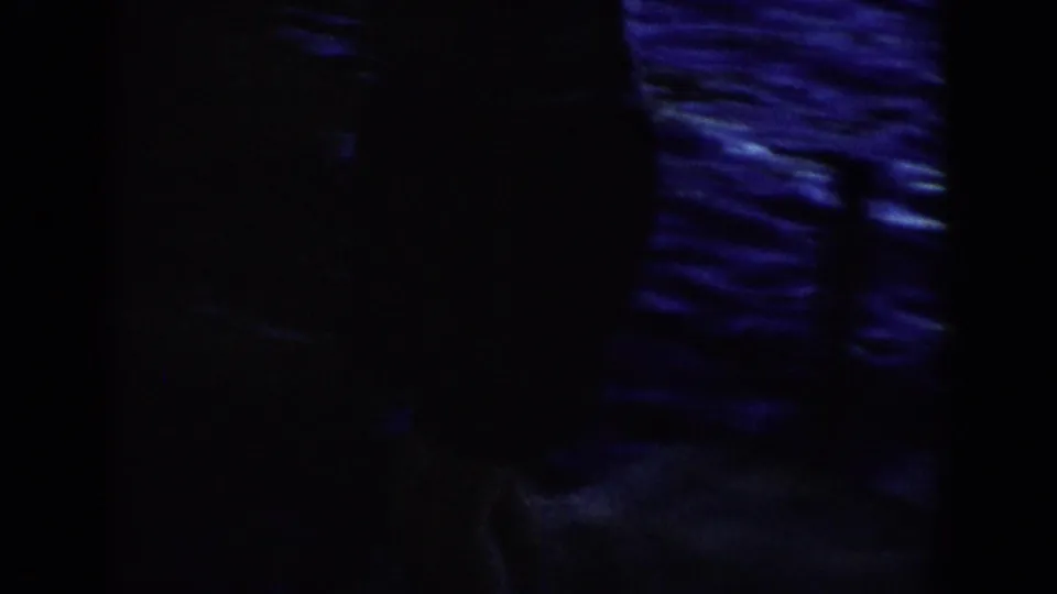 1958 Wisconsin 8mm frame with a mostly silhouetted figure against blue reflections and heavy woodland shadow.