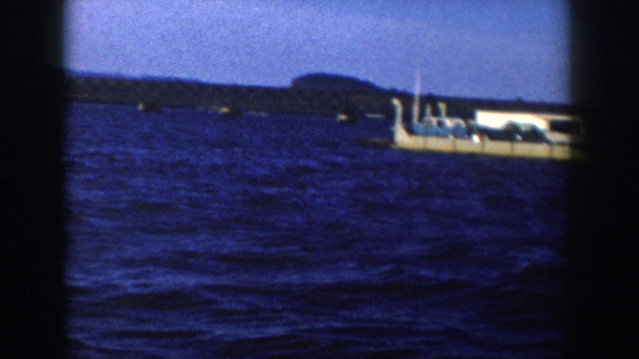 Barge-like vessel partly framed at right on rippled blue water.